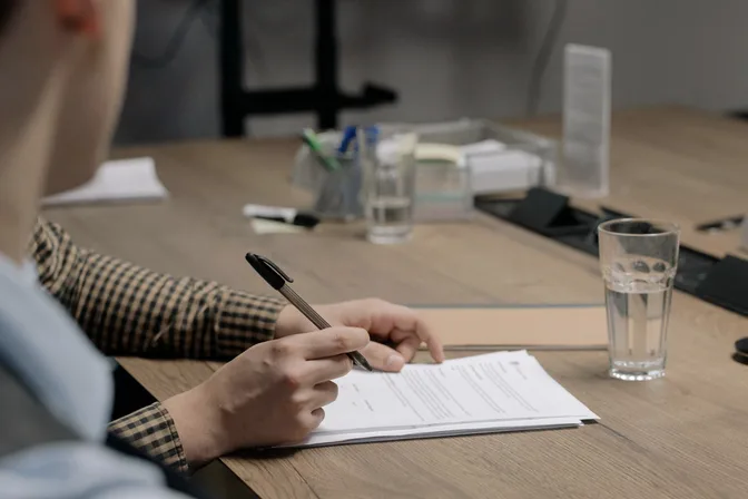 Hands writing on a printed document at a desk