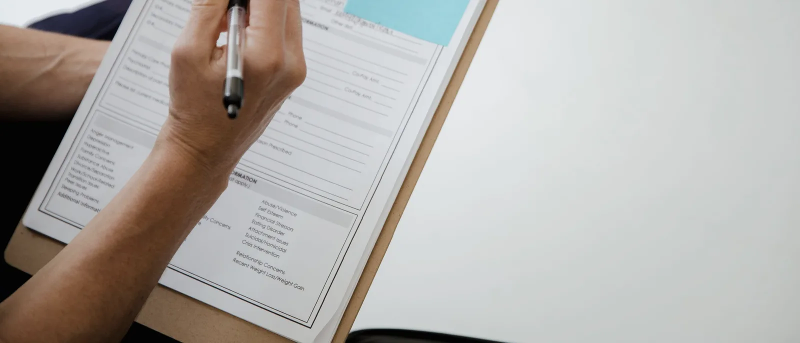 A hand filling in a form on a clipboard